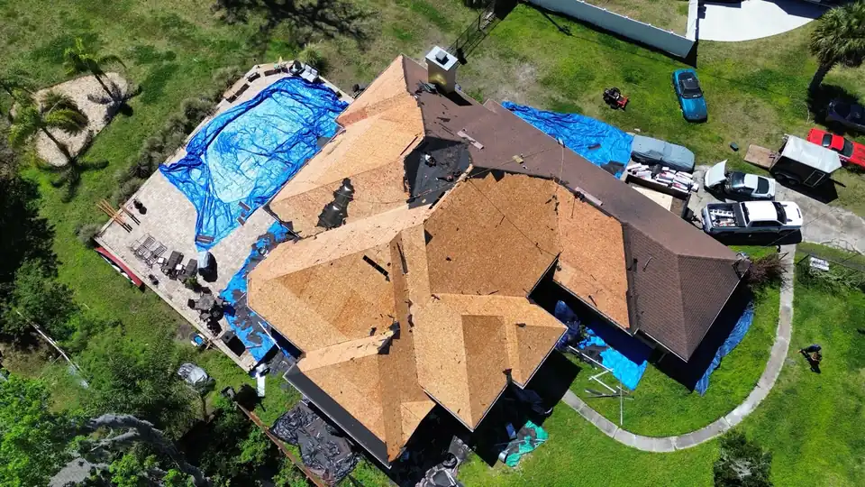 Roof replacement underway, bare decking and blue tarps below