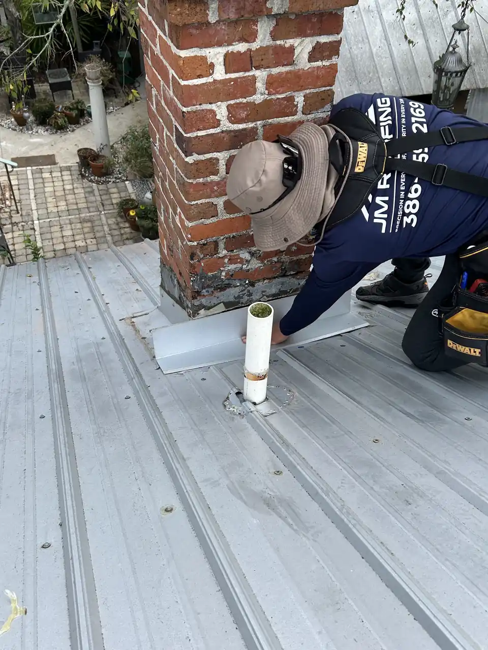 Roofer sealing a pipe boot beside a chimney