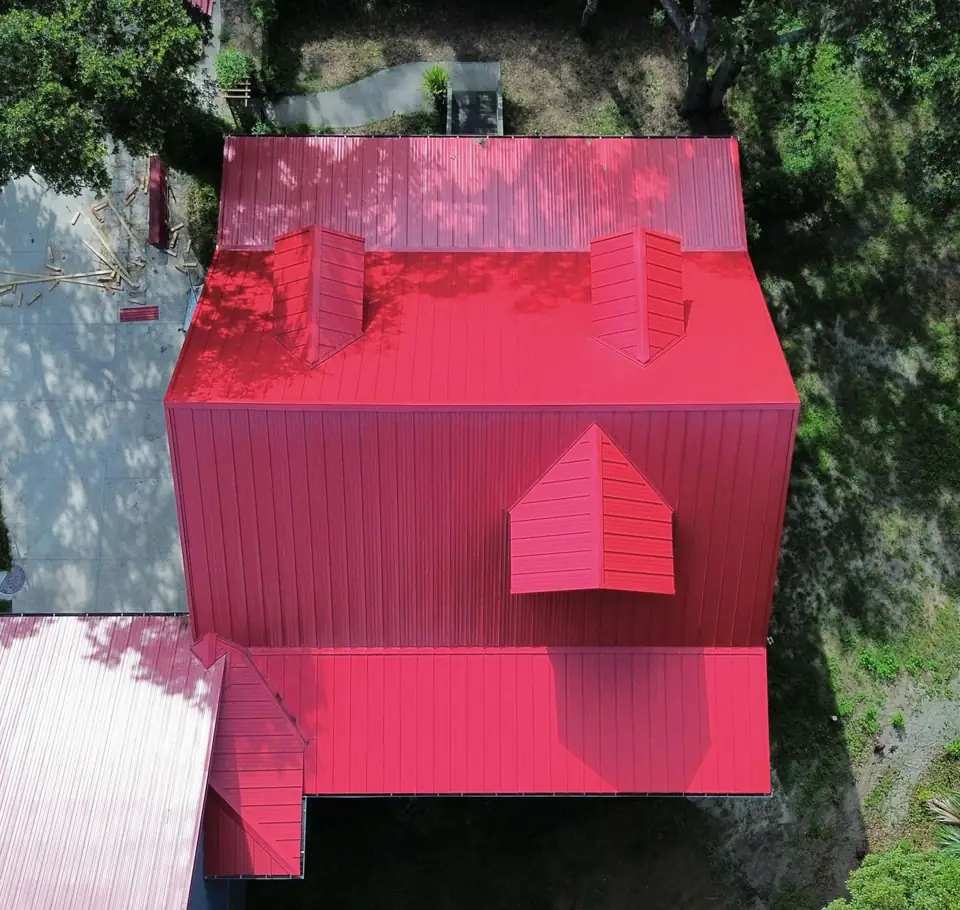 Bright red standing seam metal roof with several gables and a cupola, from above