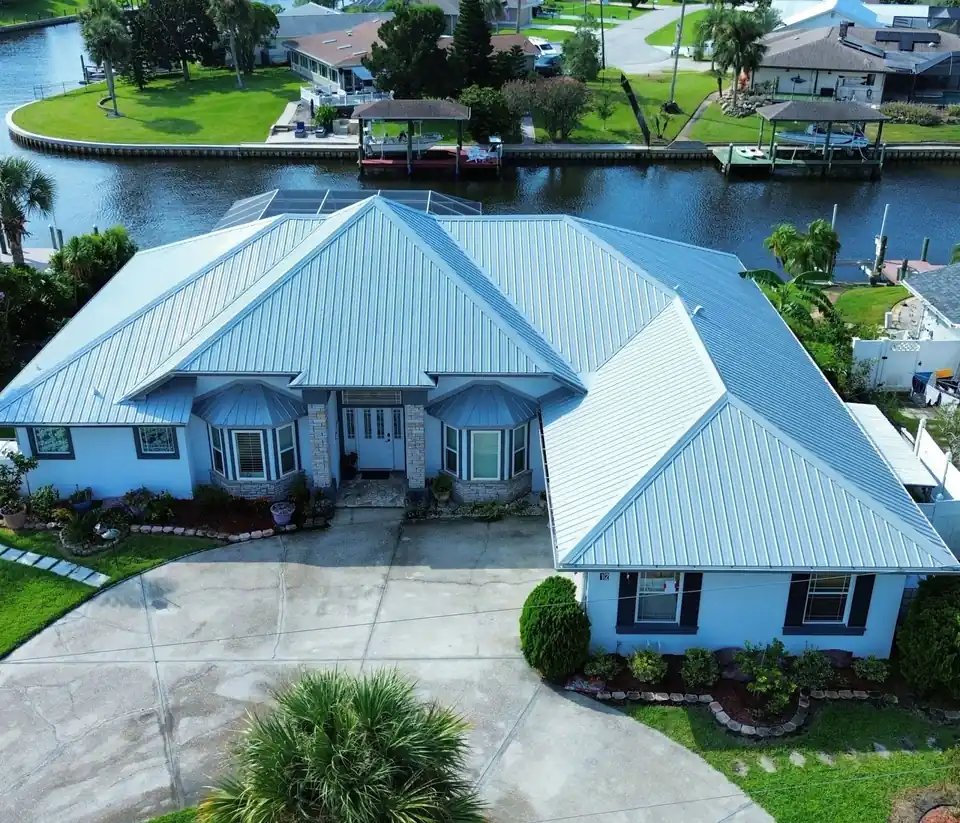 Silver metal roof on a canal-front house with palms
